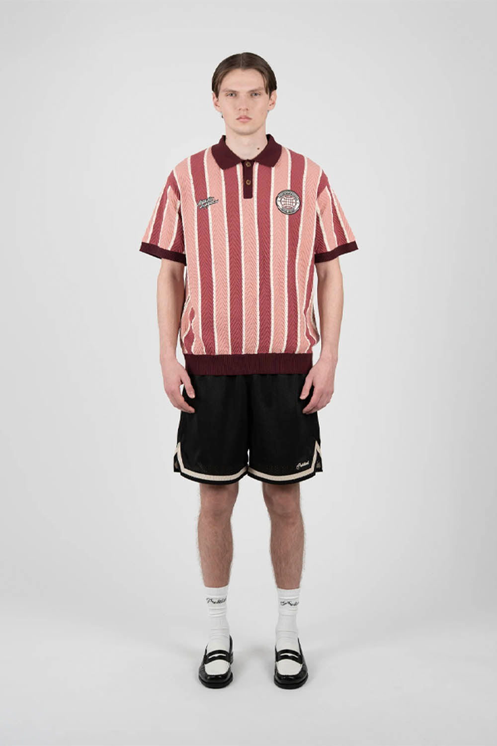 Person wearing a red and white striped polo shirt with black shorts on a white background