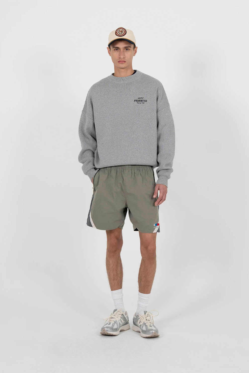Person wearing a gray sweatshirt and green shorts on a white background