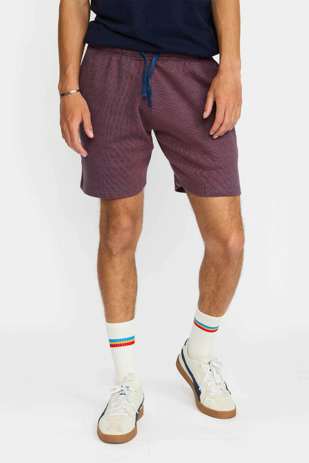 Person wearing navy Revolution Jacquard shorts, white socks with colorful stripes, and white sneakers on a white background