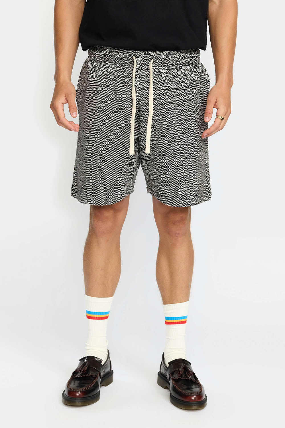 Person wearing gray patterned shorts with a white background