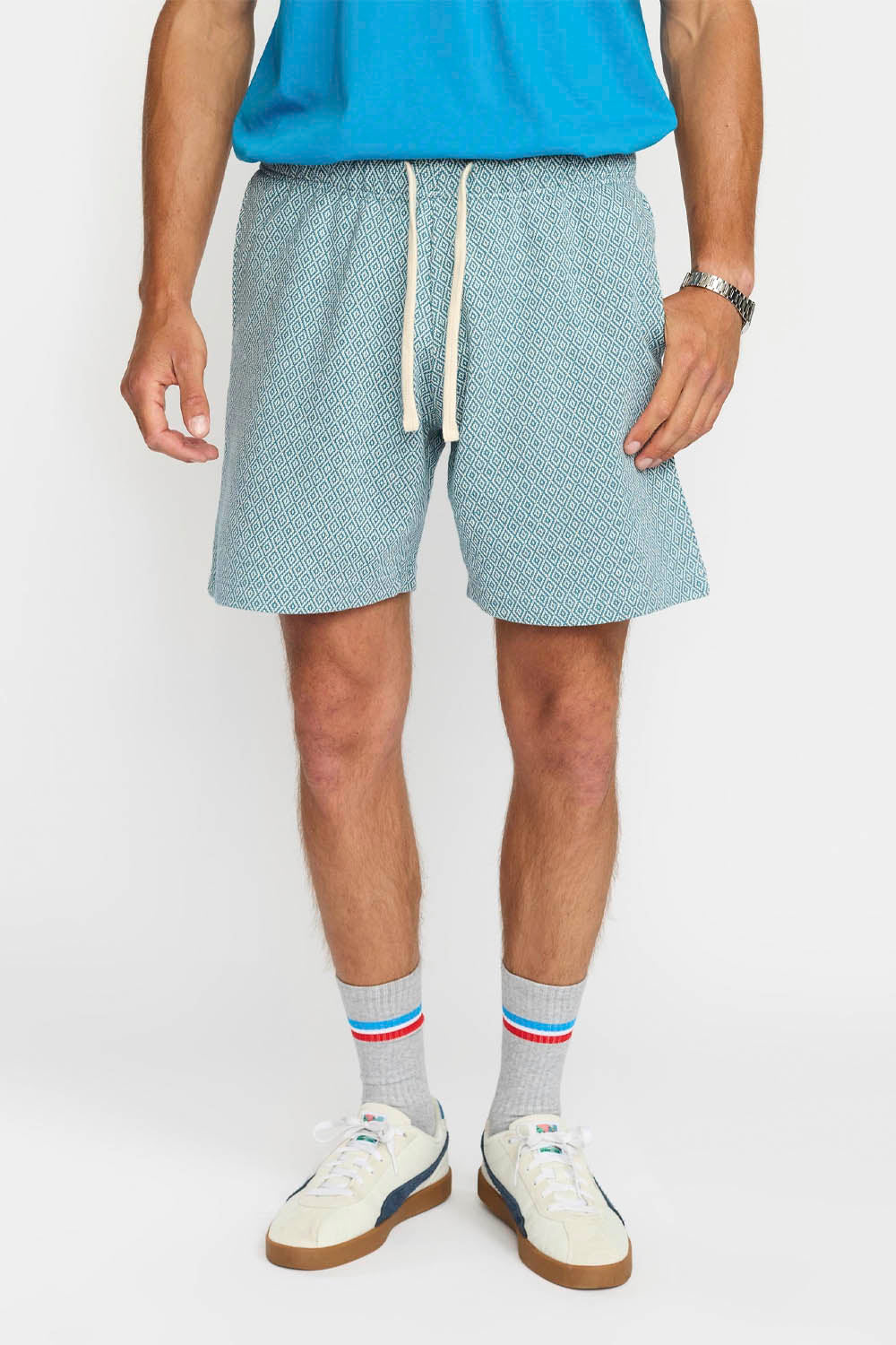 Person wearing light blue shorts with a white drawstring, white sneakers, and striped socks on a white background.