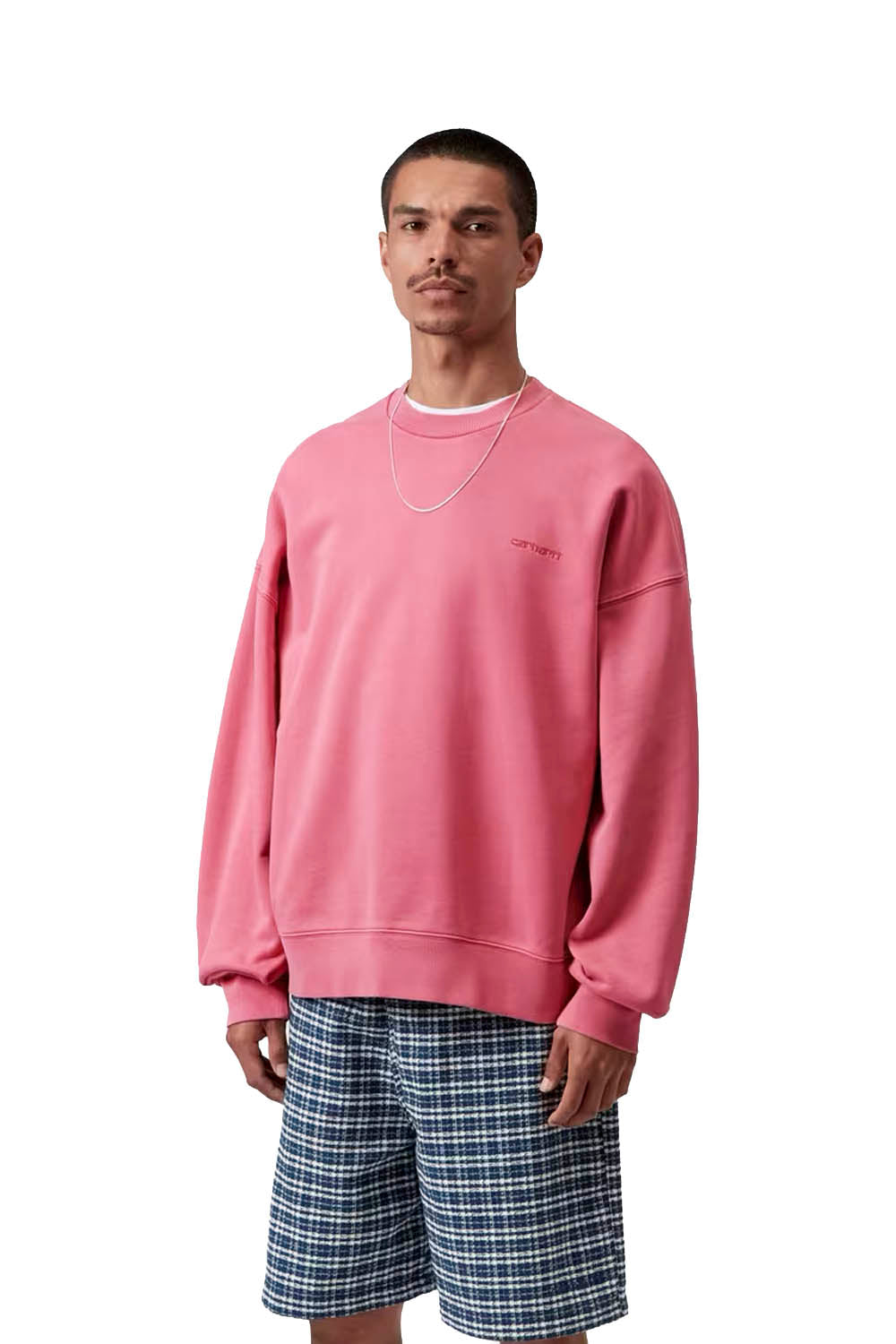 Man wearing a pink sweatshirt and plaid shorts on a white background