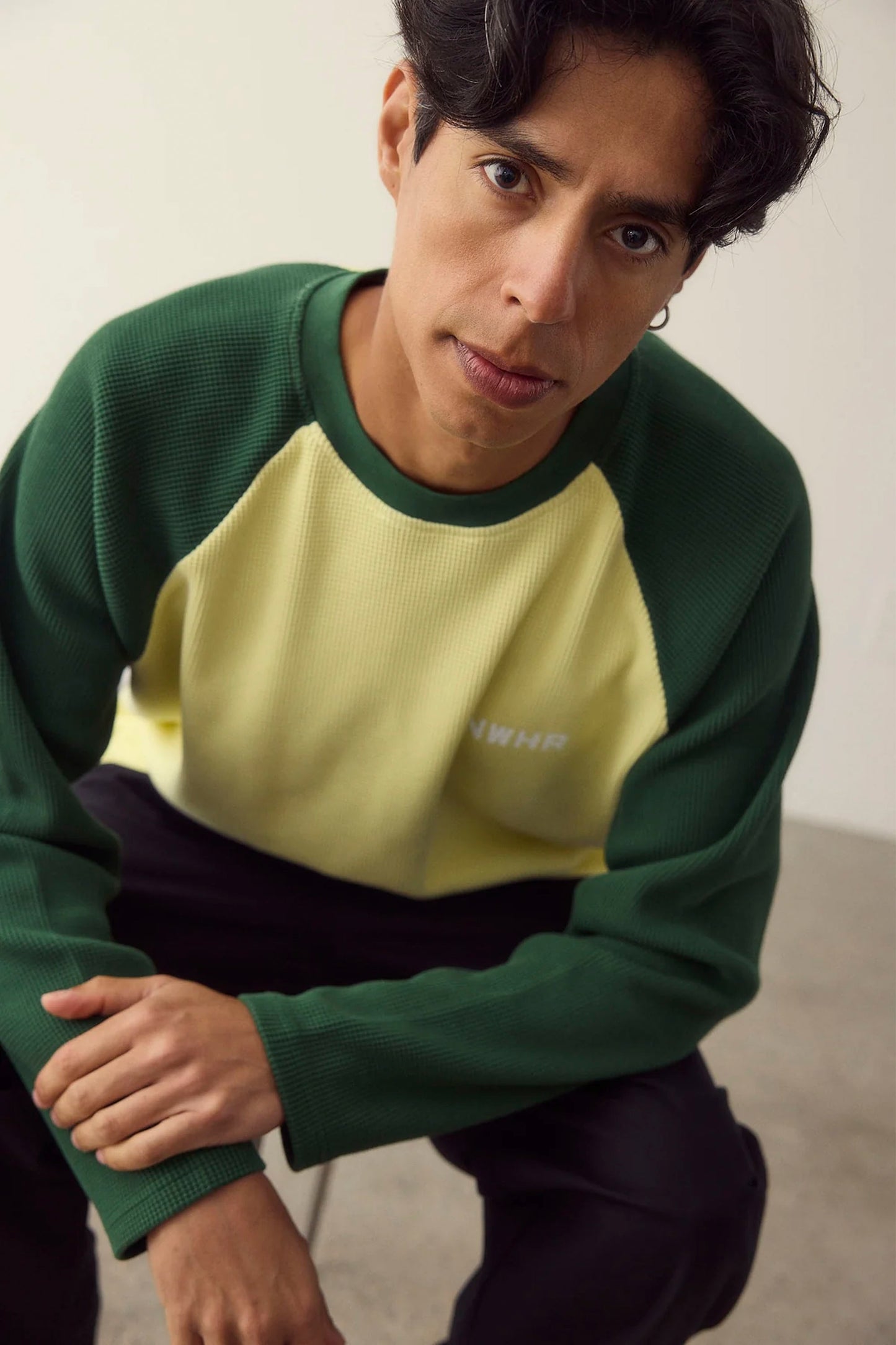 Person wearing a green and yellow NWHR sweater with a neutral background