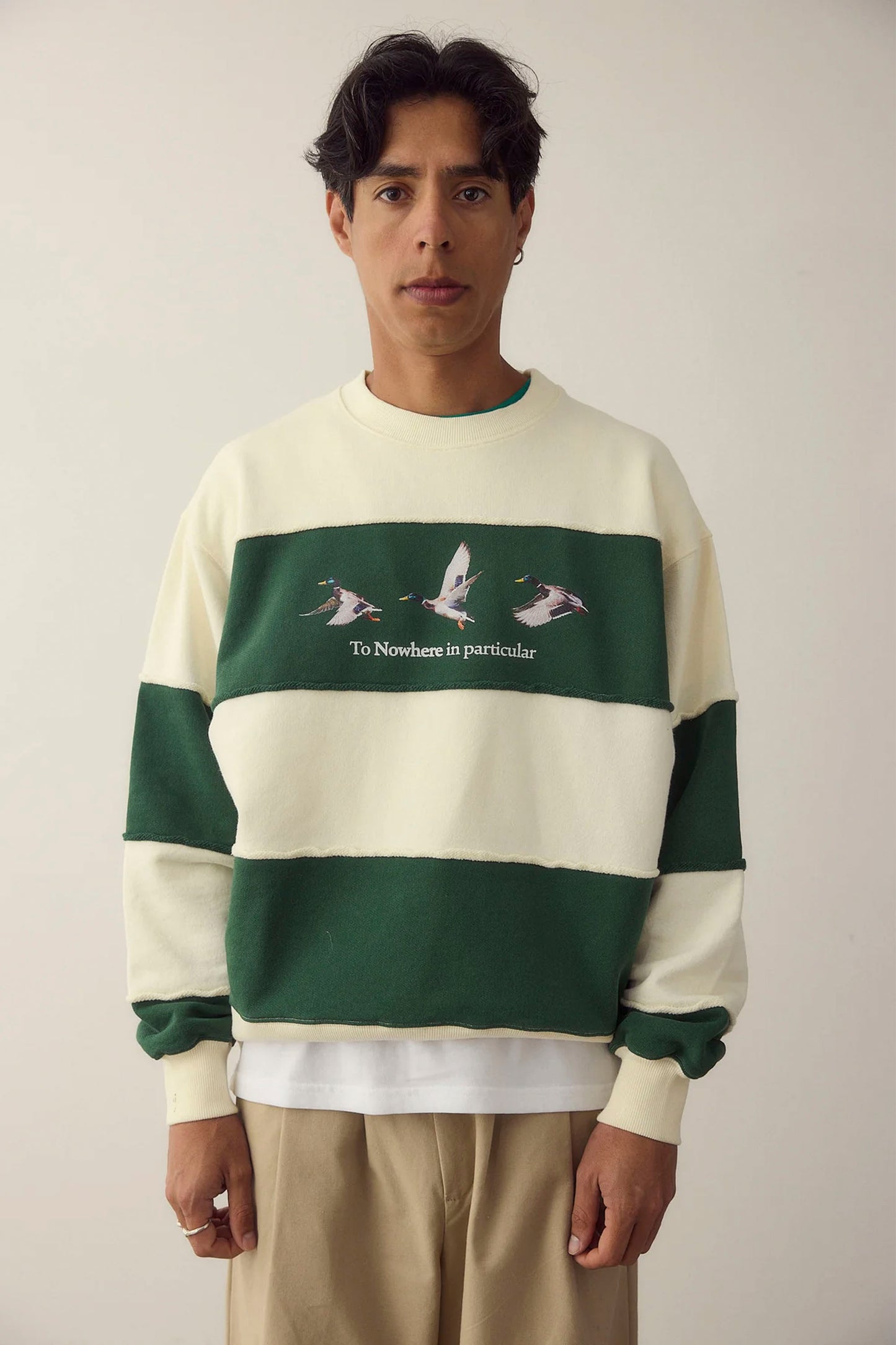 Person wearing a green and white NWHR sweater with text and graphic design on a plain background