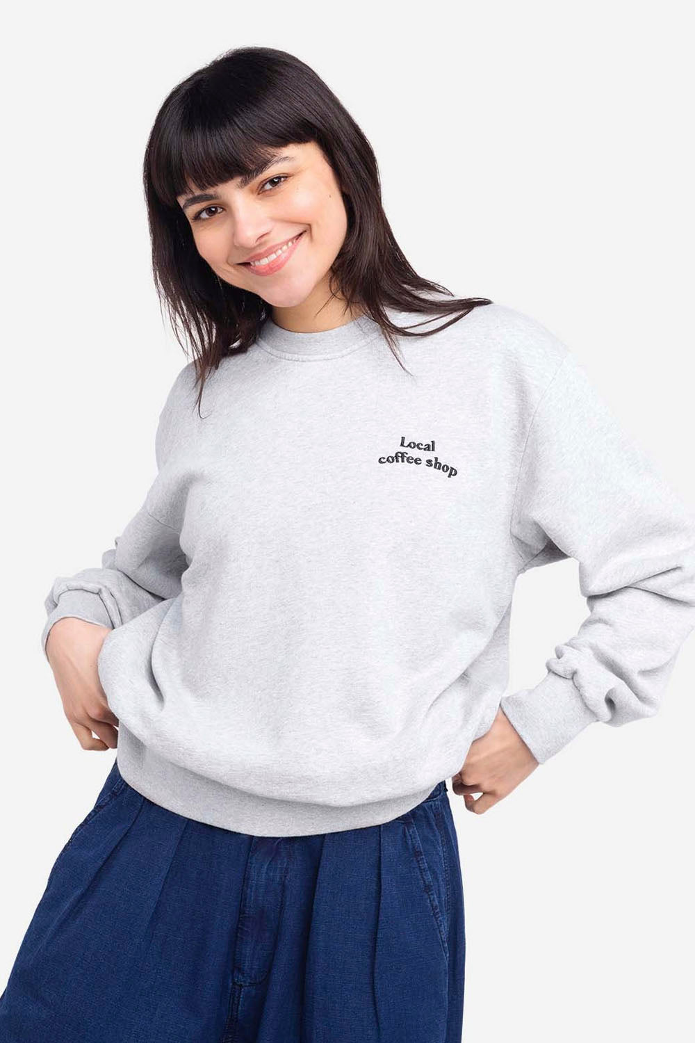 Person wearing a gray sweatshirt with text, standing against a white background