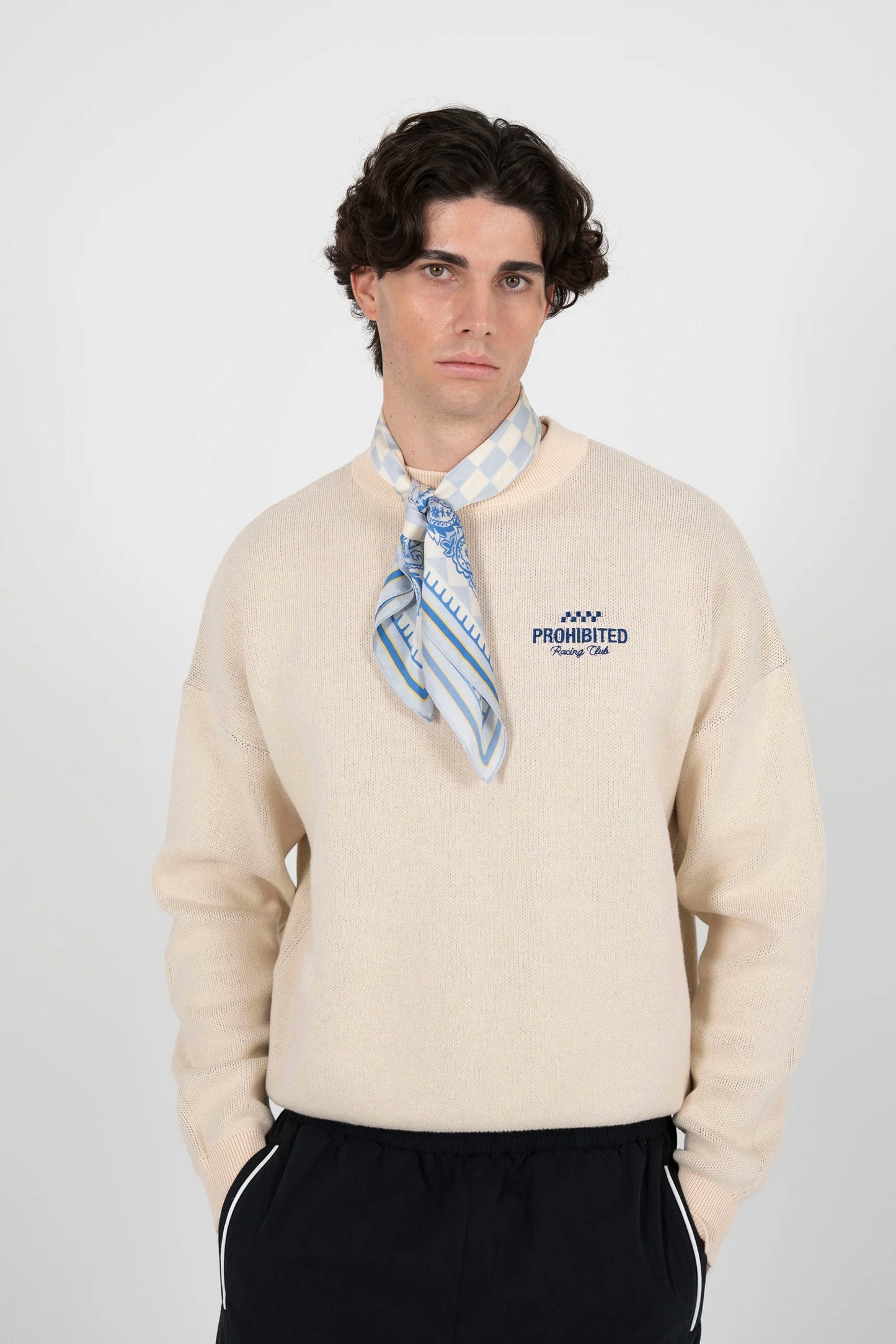 Man wearing PROHIBITED Vortex knit sweater in cream with In a Rush jacquard back design