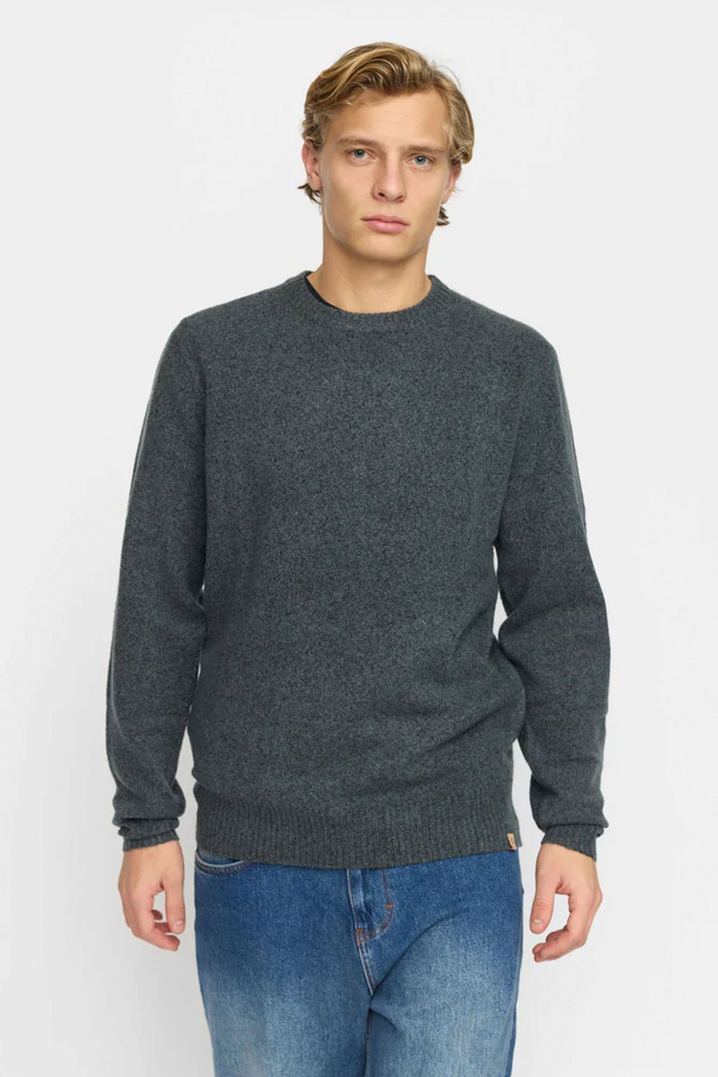 Man wearing Revolution dark gray sweater and blue jeans Pukas Surf Shop