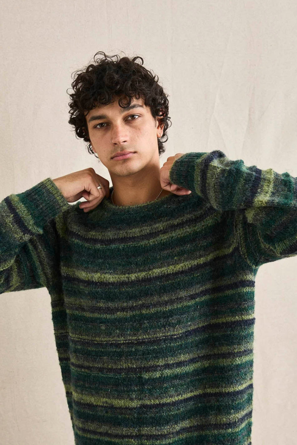 Man wearing a green and blue striped sweater against a neutral background