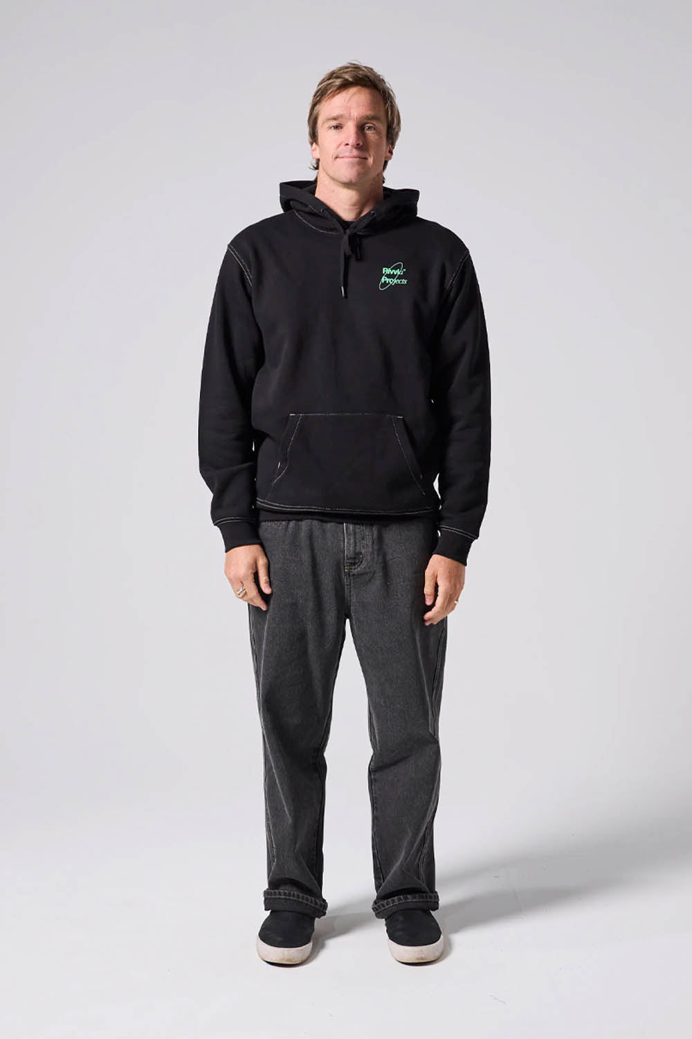 Person wearing a black hoodie and gray pants on a white background
