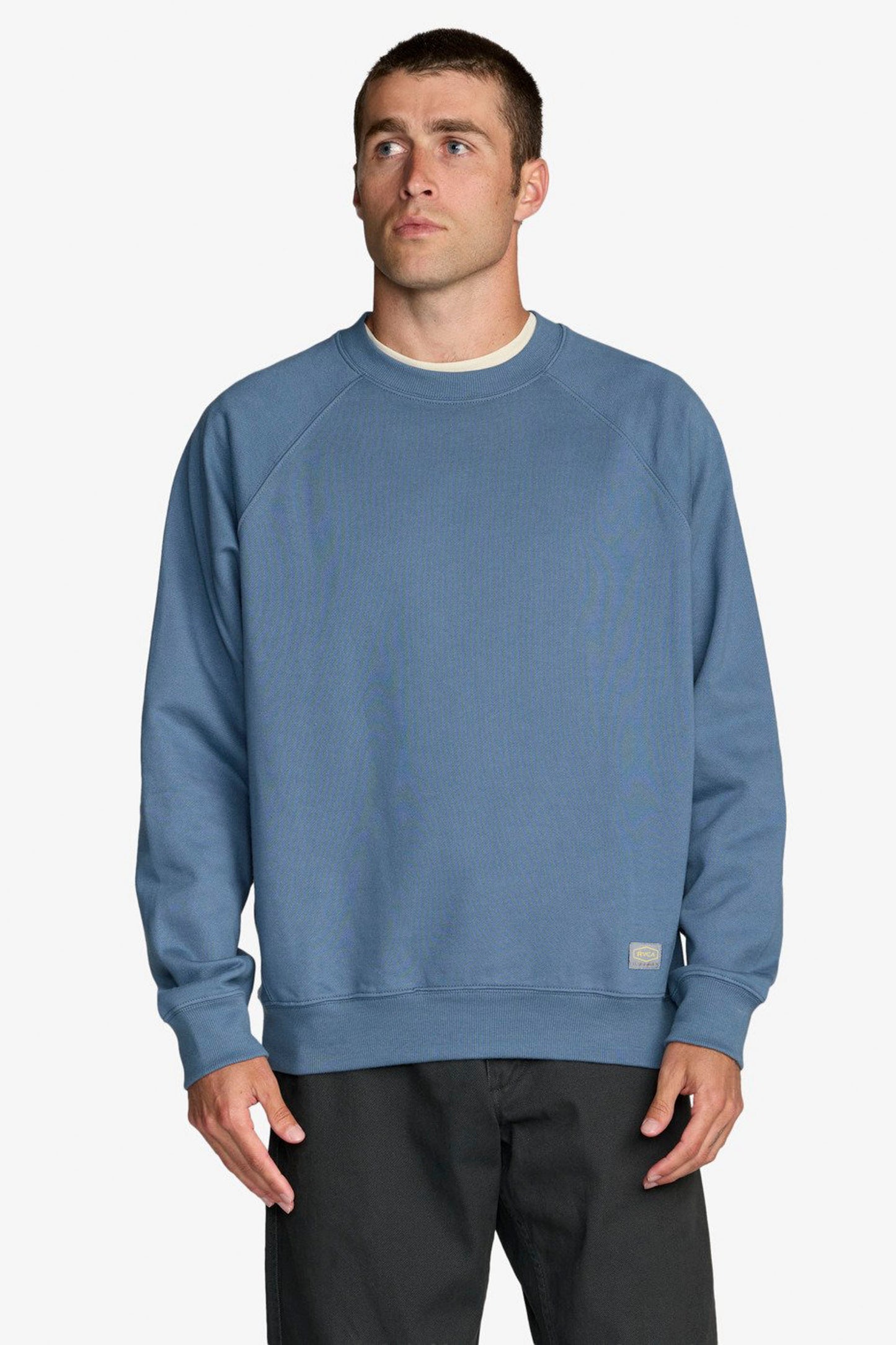 Man wearing a Blue Rvca Dayshift sweater in a white background 