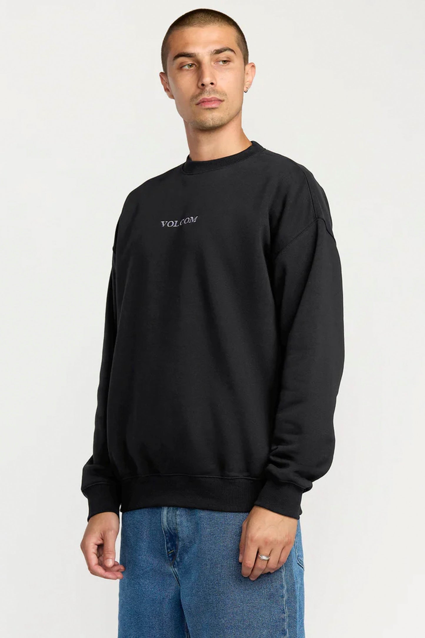 Man wearing a black Volcom Stone sweatshirt with a logo on a white background
