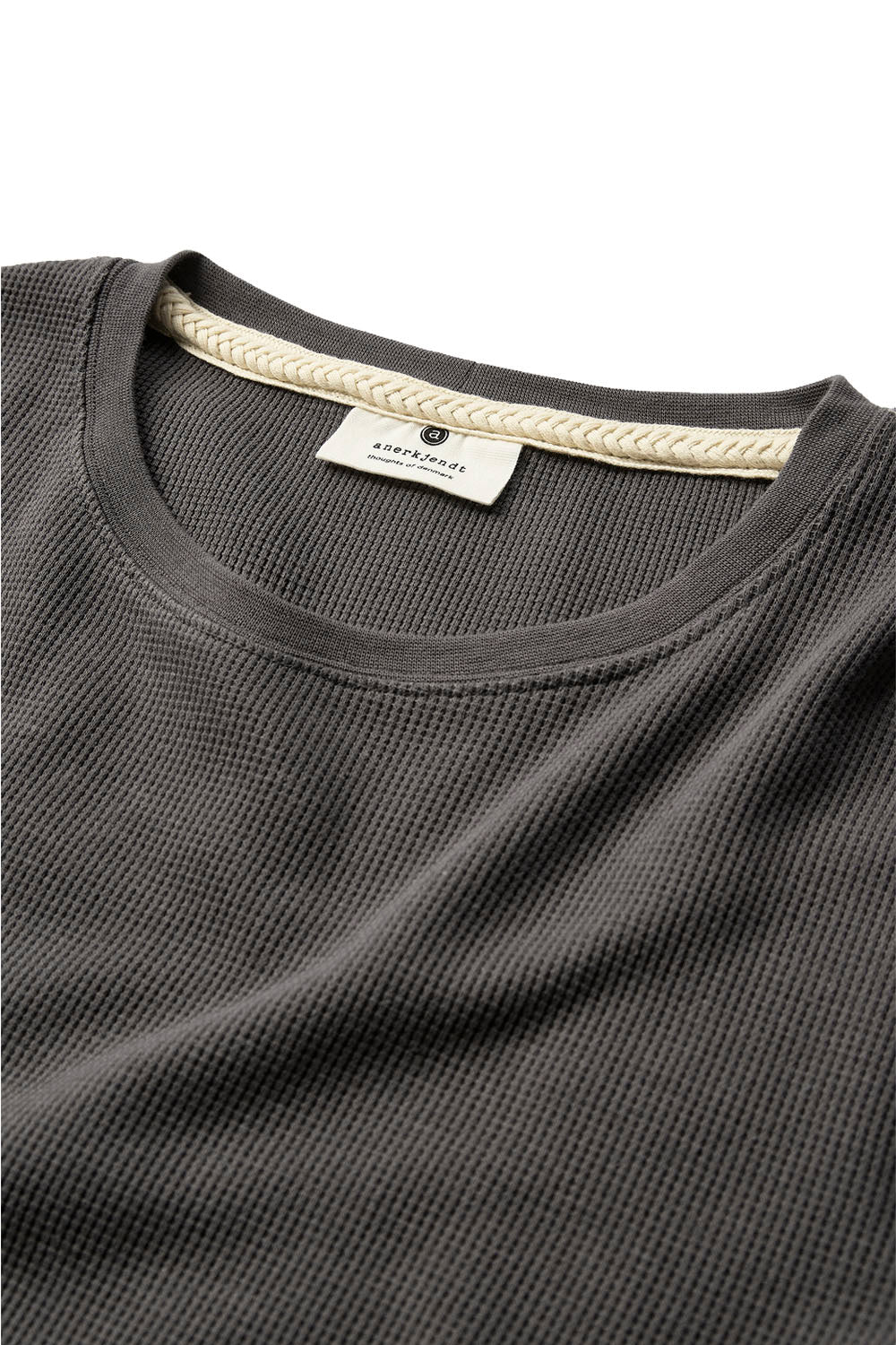 Close-up of a dark gray waffle-knit crewneck shirt by Alok, showing the textured fabric, ribbed collar, and a cream-colored inner neck label.