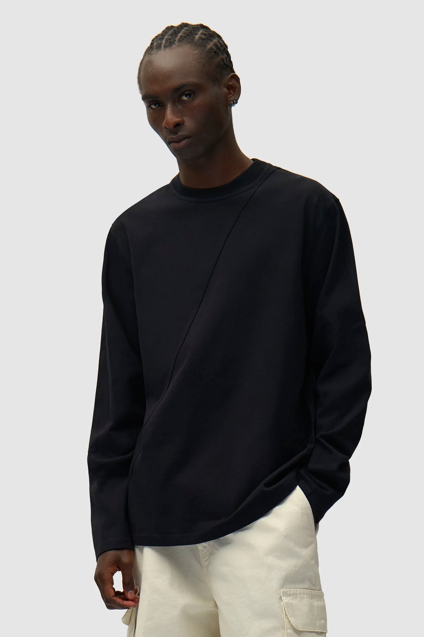 Person wearing a black ARTE circle logo longsleeve tee and light-colored pants on a plain background