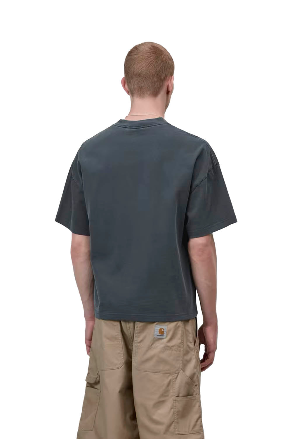 Man wearing a dark gray t-shirt and beige pants on a white background