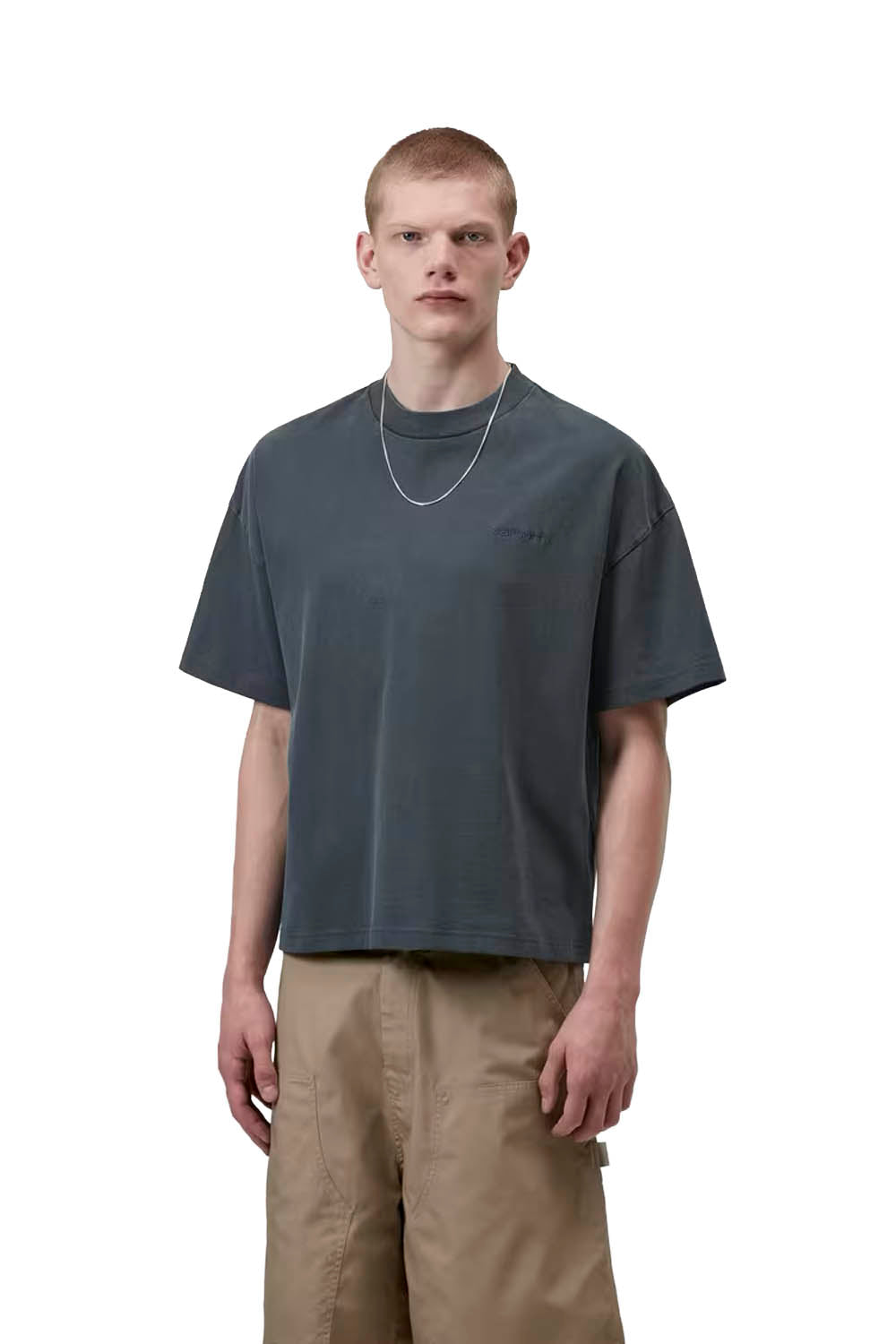 Man wearing a dark gray t-shirt and beige pants on a white background