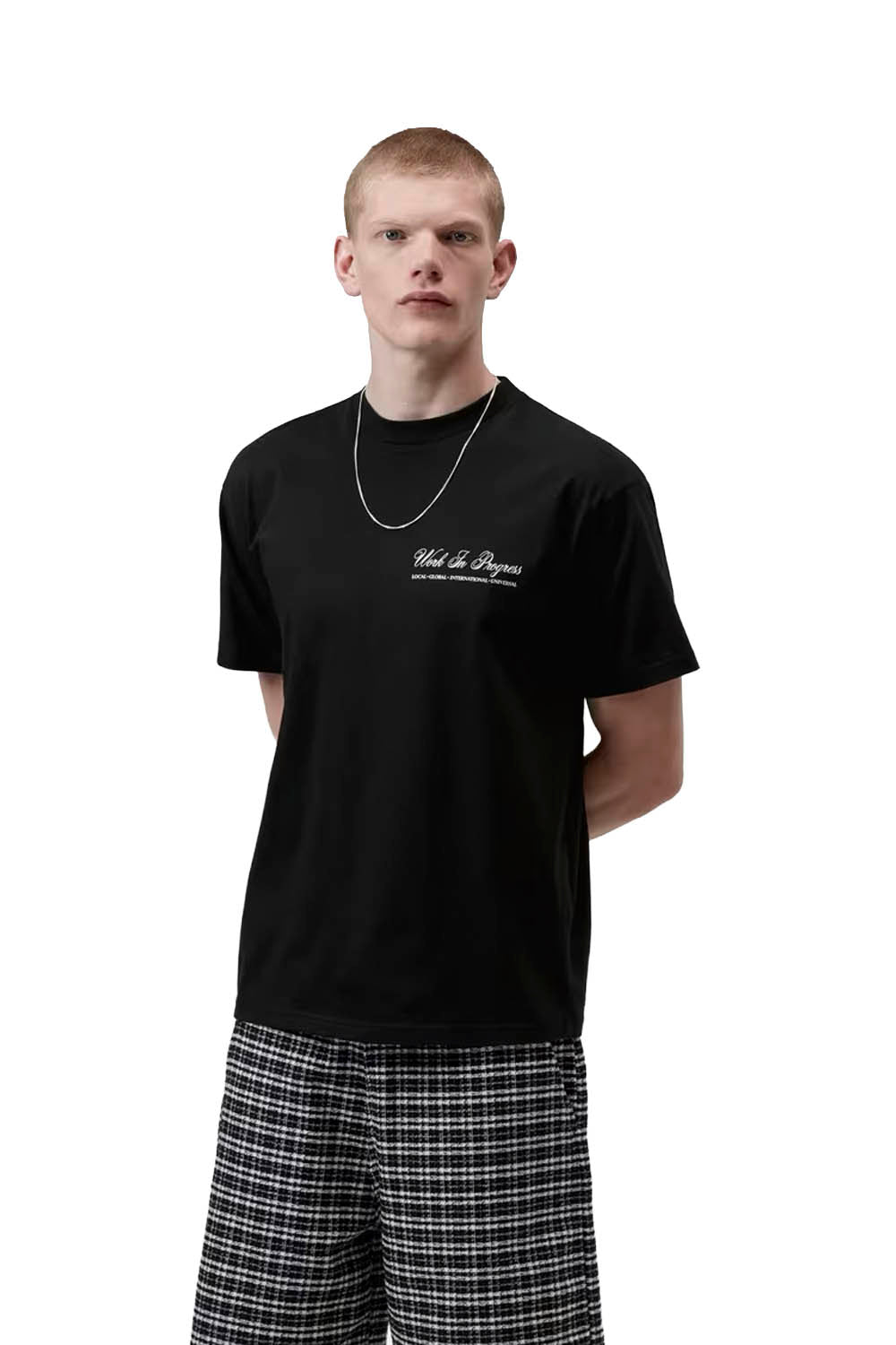 Man wearing a black t-shirt with text and plaid pants on a white background