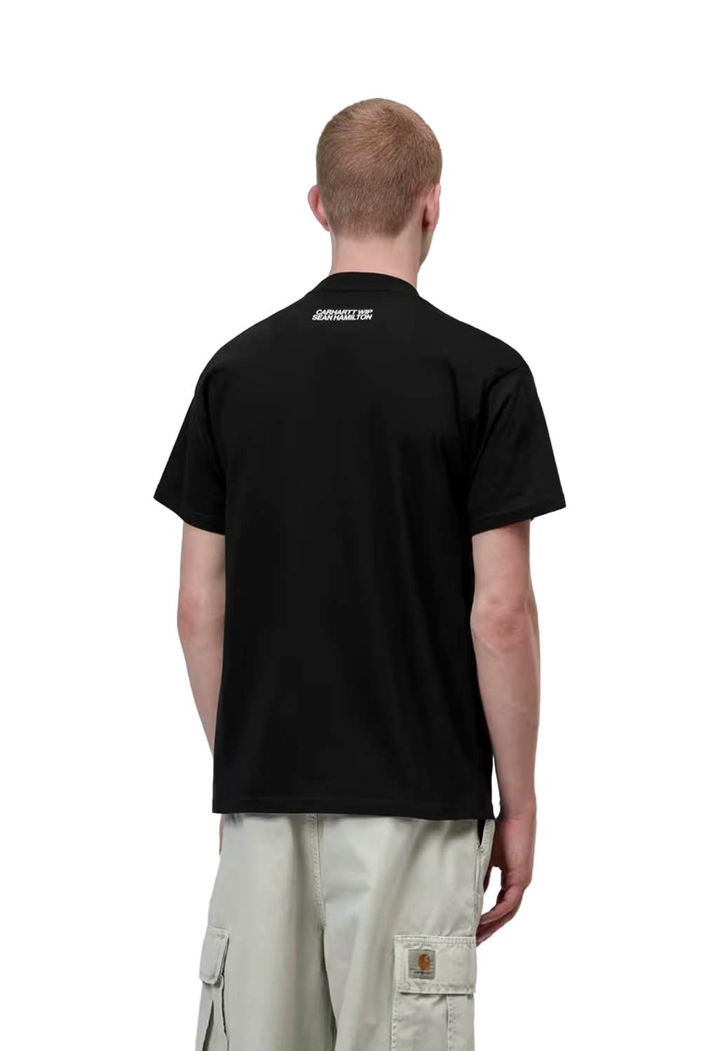 Person wearing a black t-shirt with a logo on the back, standing against a white background