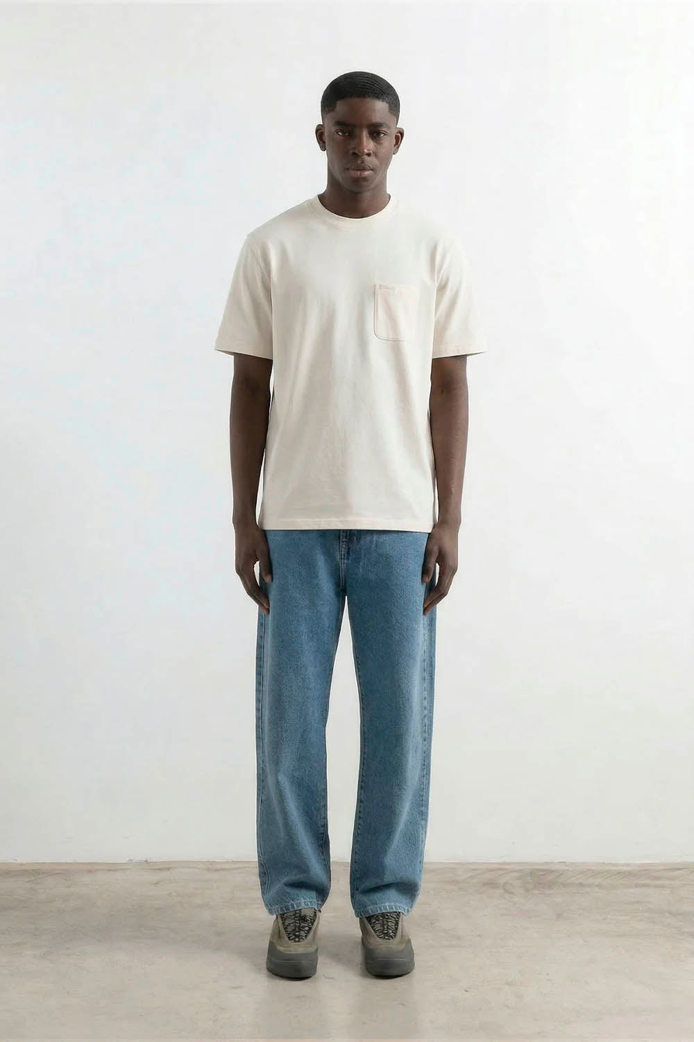 Man wearing a plain white t-shirt and blue jeans standing against a white background