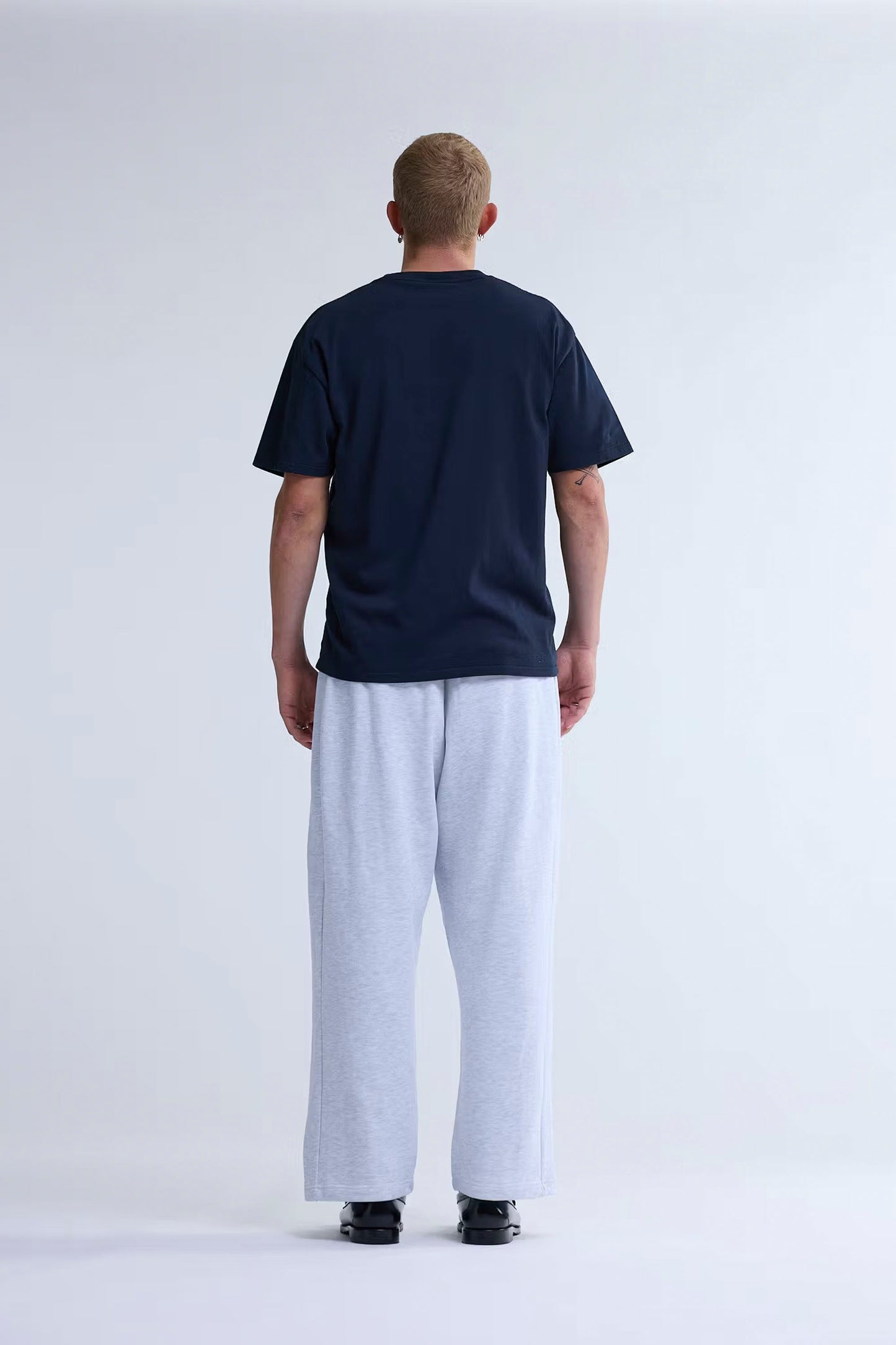 Person wearing New Amsterdam Surf Association Chop Tee in Navy Blazer and light-colored pants on a white background - back view