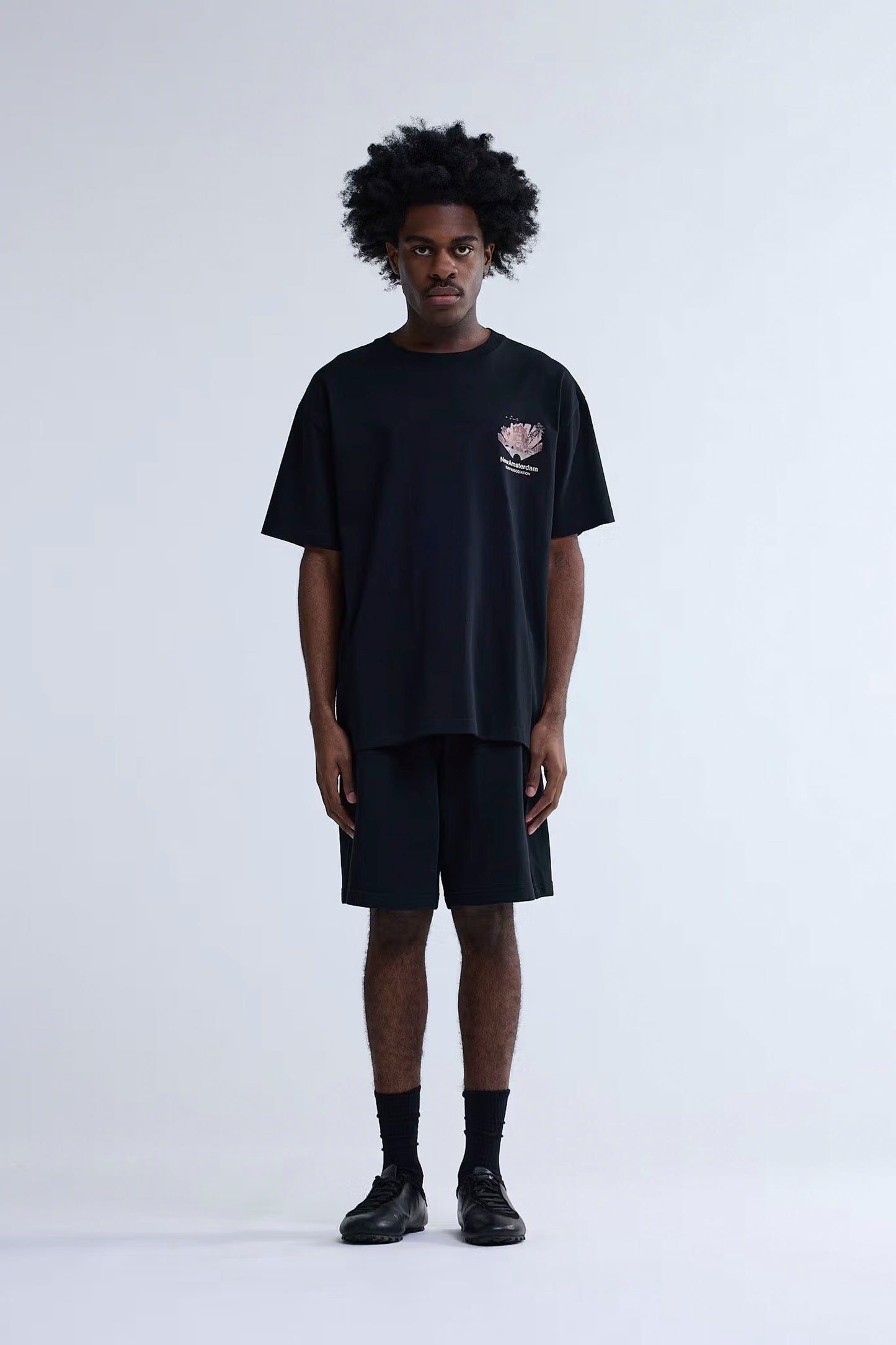 Person wearing a black New Amsterdam Surf Association Tropical Tee on a white background