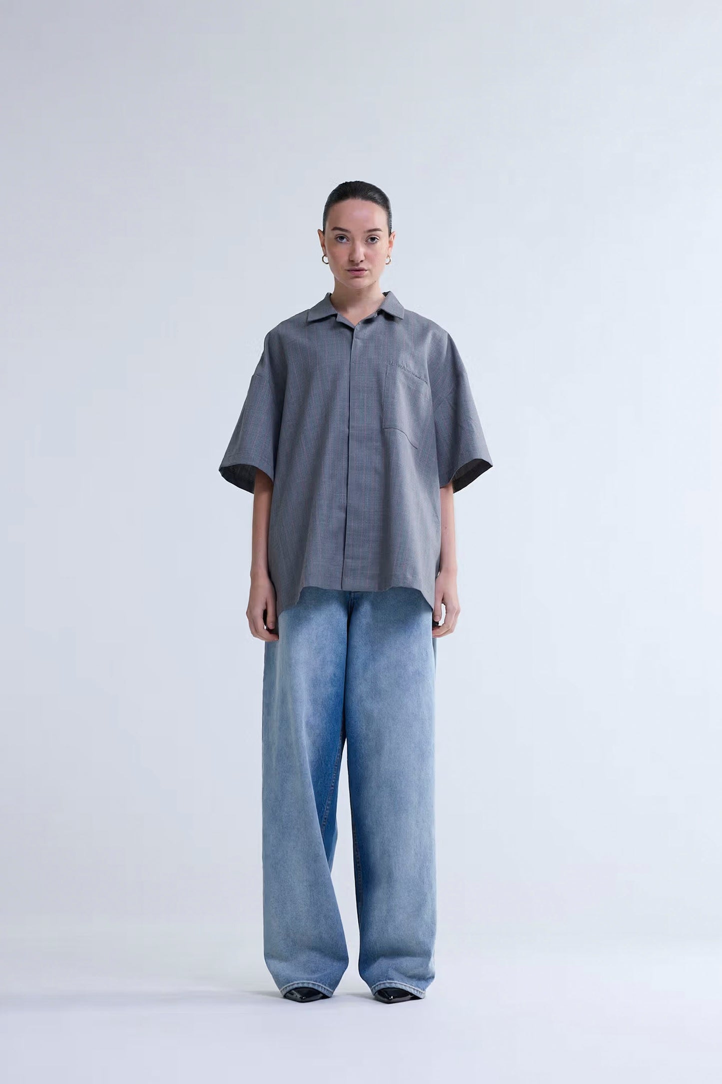 Person wearing a gray shirt and light blue jeans on a white background