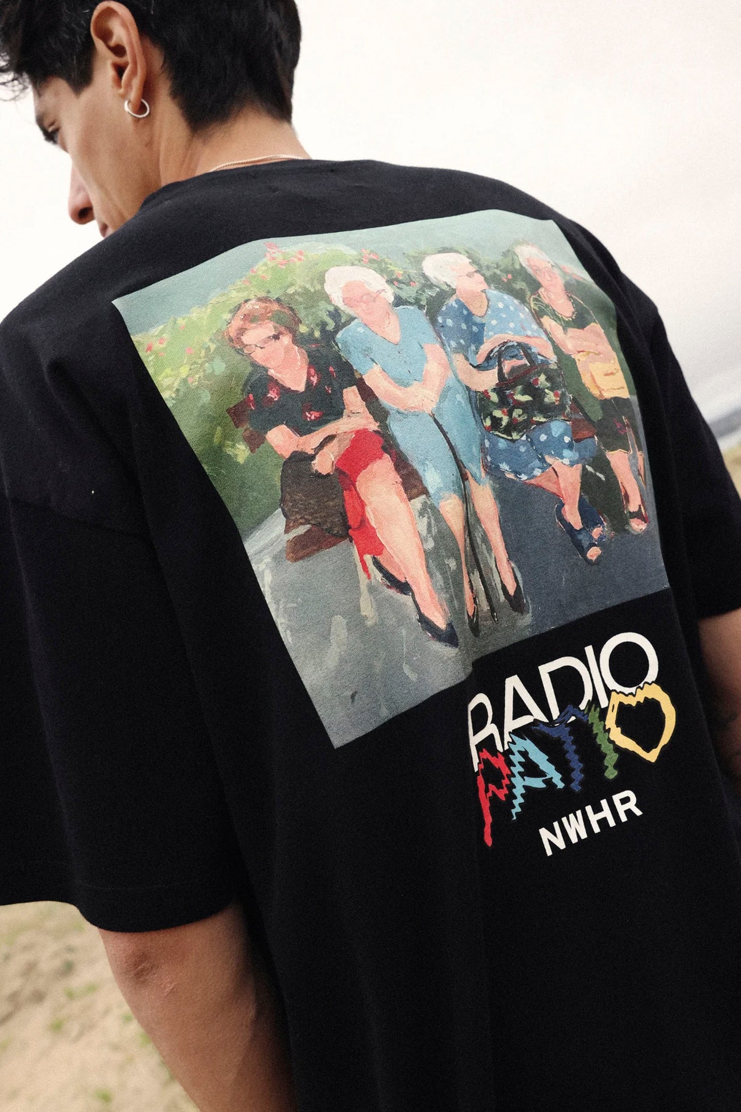 Black NWHR t-shirt with a graphic of four people and 'Radio Haiti' text on the back.
