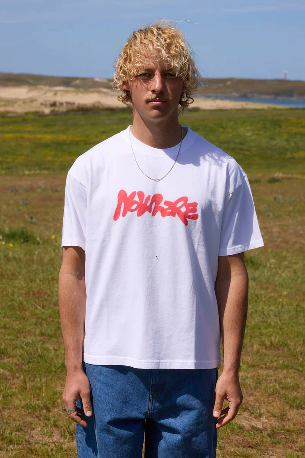 Person wearing a white t-shirt with red text in an outdoor setting