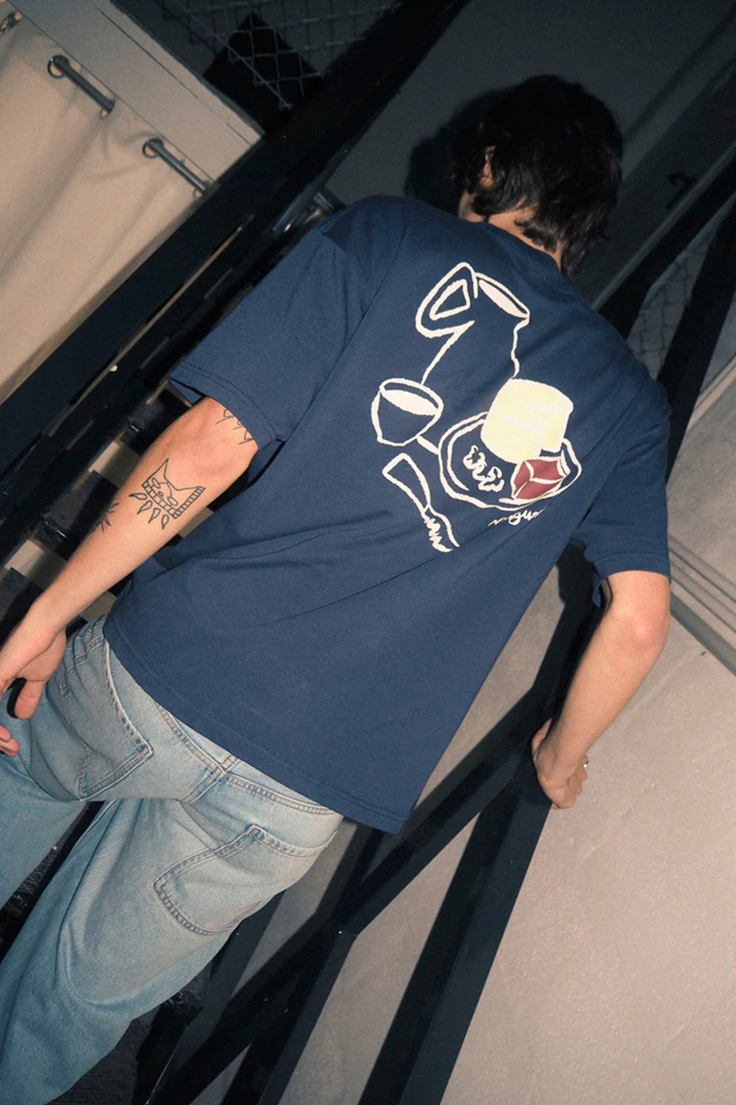 Person wearing a navy NWHR blue t-shirt with a graphic design on the back, standing indoors.
