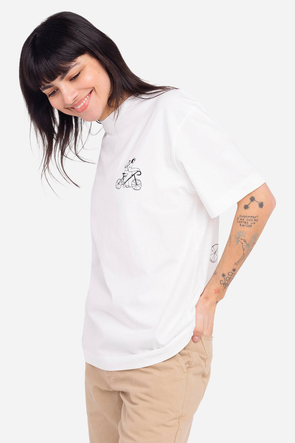 Person wearing a white t-shirt with a small graphic design on a plain background