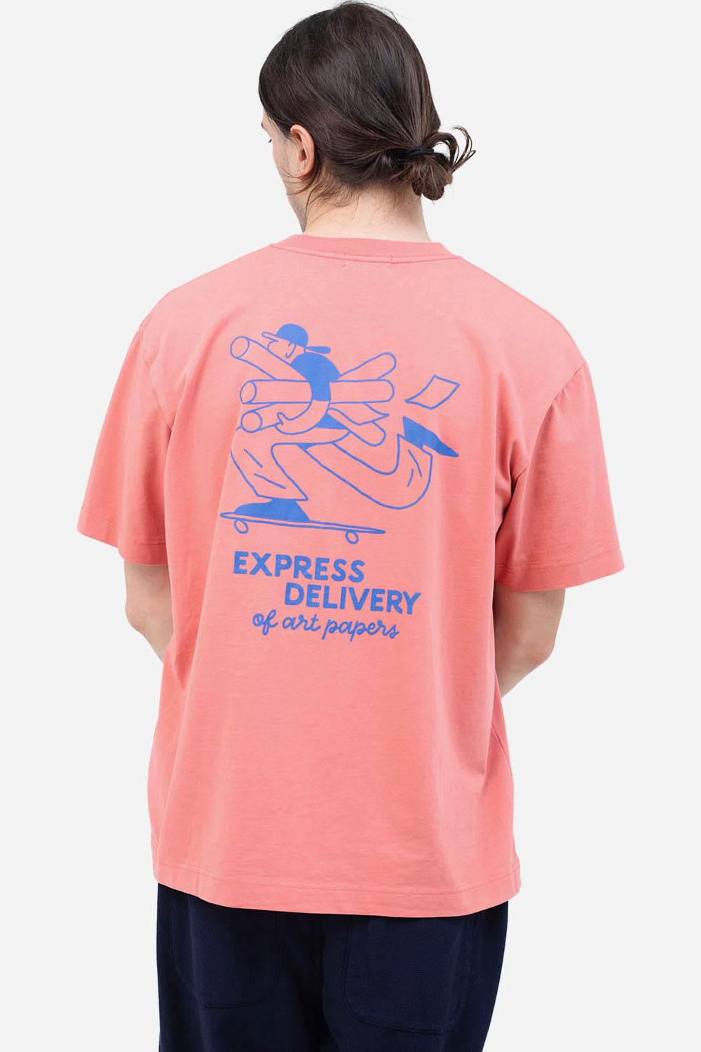 Person wearing a pink t-shirt with blue graphics and text on the back