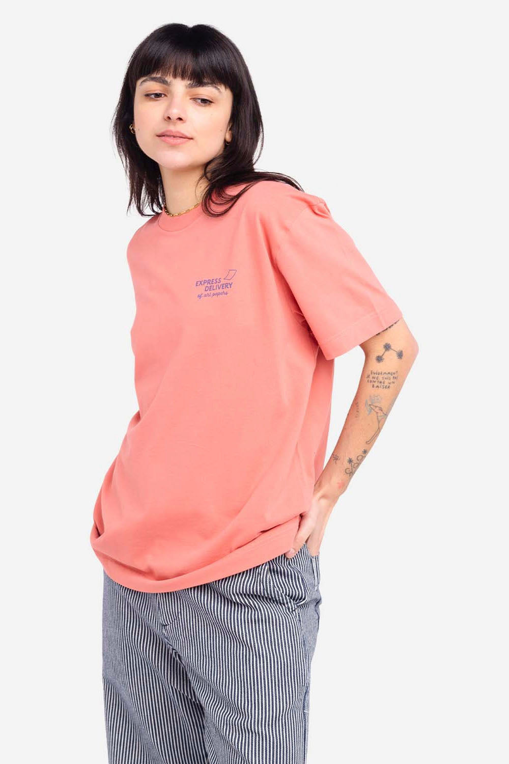 Person wearing a pink t-shirt with a small logo on a white background