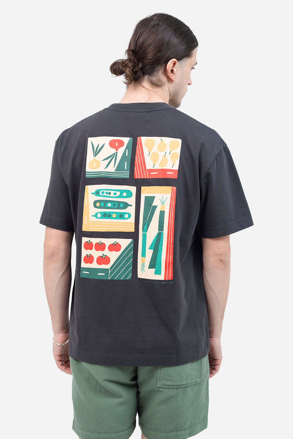 Person wearing a dark gray t-shirt with colorful geometric patterns on the back, standing against a white background.