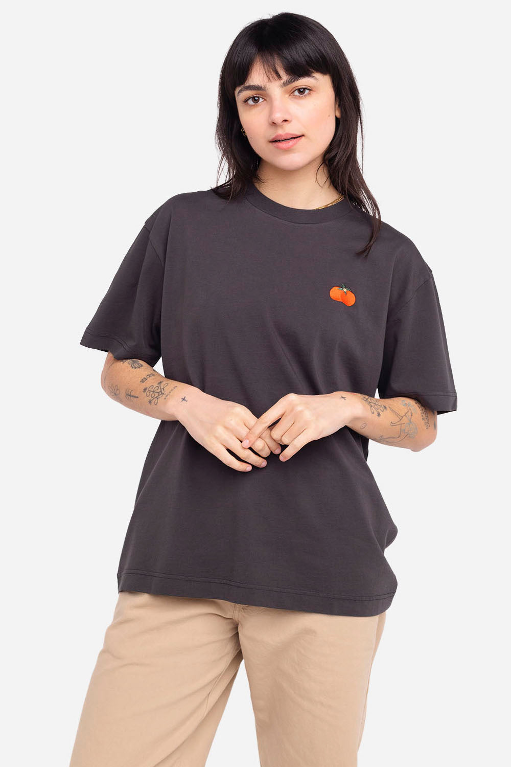 Person wearing a dark gray t-shirt with an orange logo on a white background