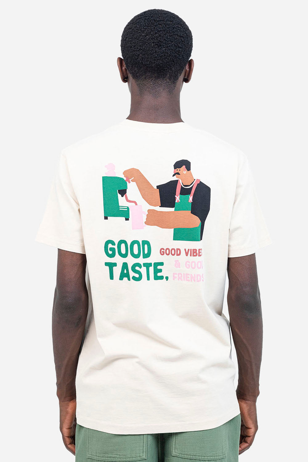 Person wearing a white t-shirt with a graphic design and text on the back, on a plain background.