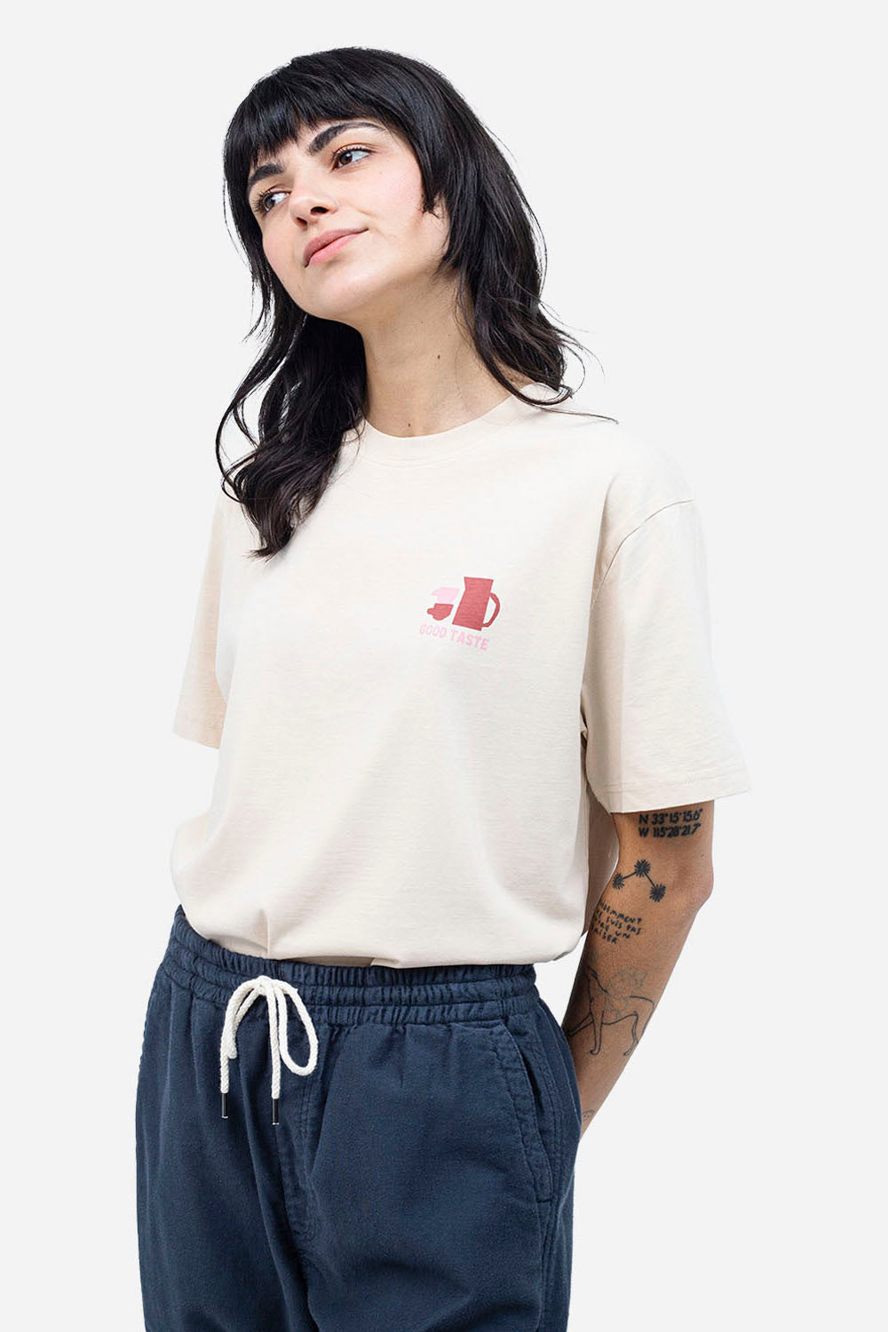 Person wearing a white t-shirt with a red logo and dark pants on a white background