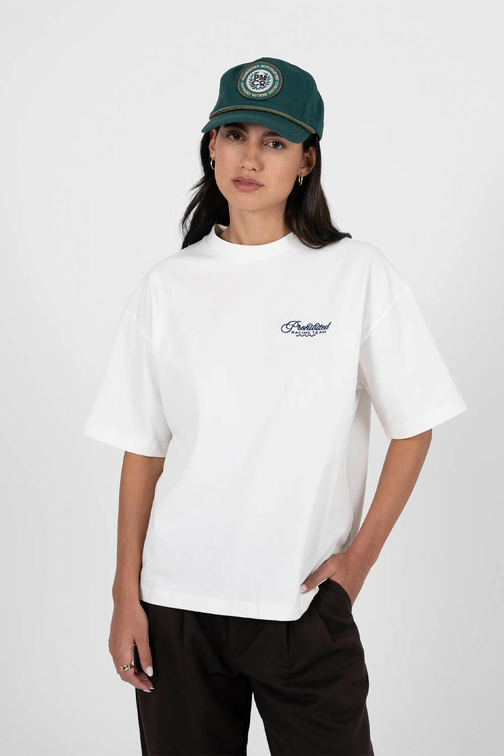 Person wearing a white t-shirt and green cap with a logo on a white background