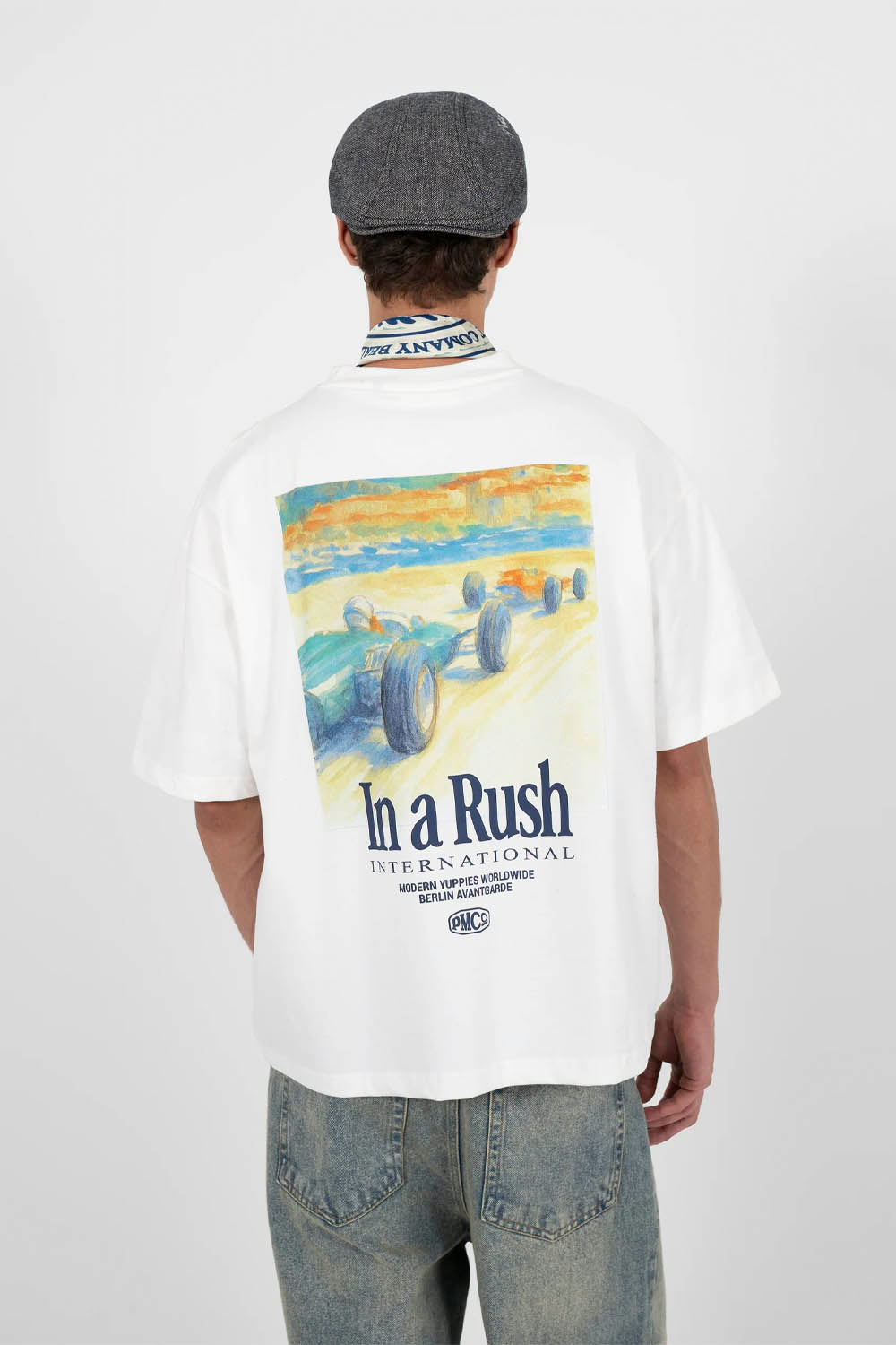 Person wearing a white t-shirt with a colorful graphic and text on the back, standing against a plain background.