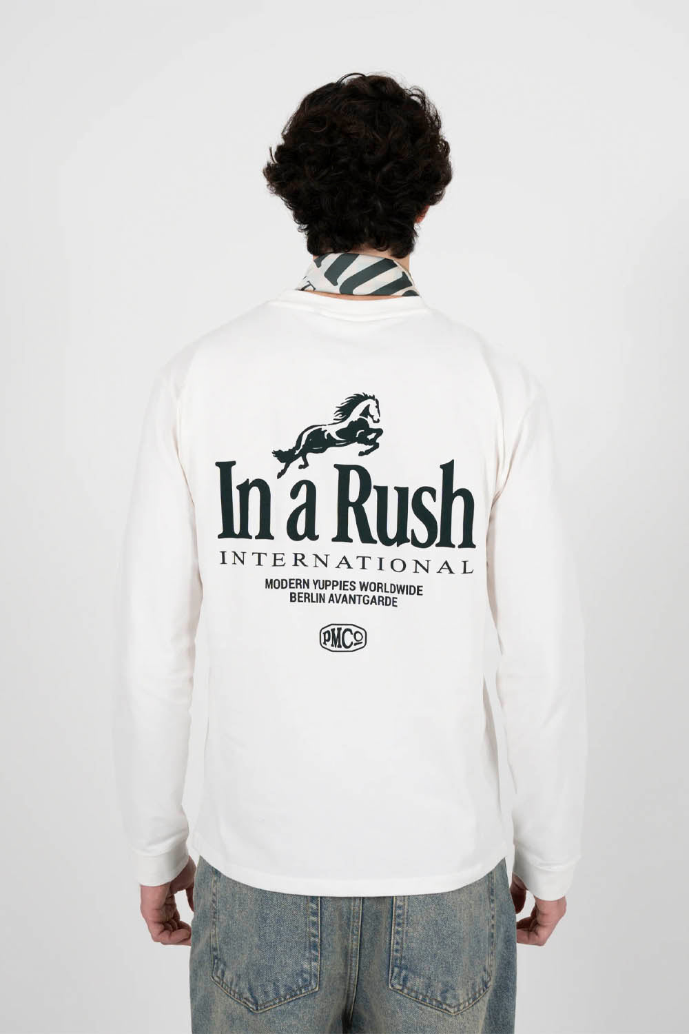 Person wearing a white long-sleeve shirt with 'In a Rush International' logo on the back, standing against a plain background.