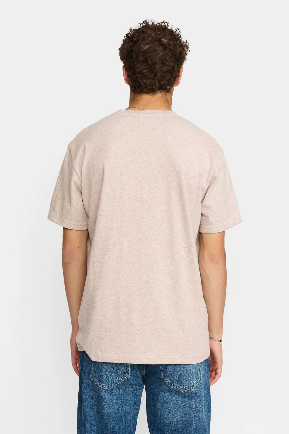 Person wearing a beige t-shirt and blue jeans on a white background