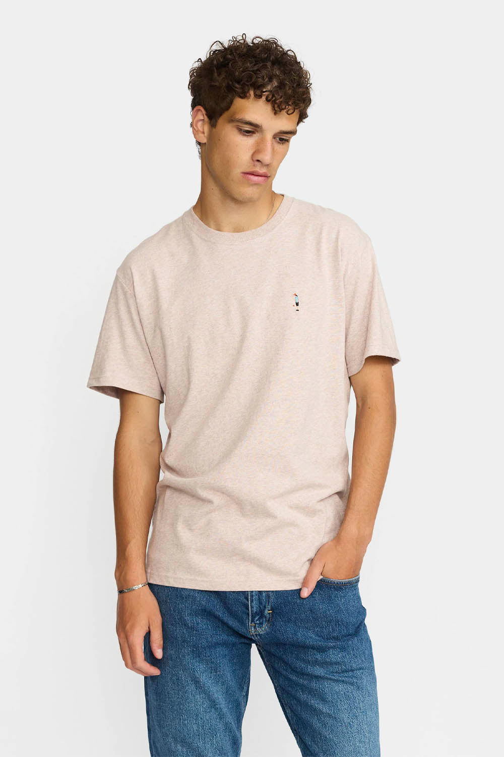 Man wearing a beige t-shirt and blue jeans on a white background