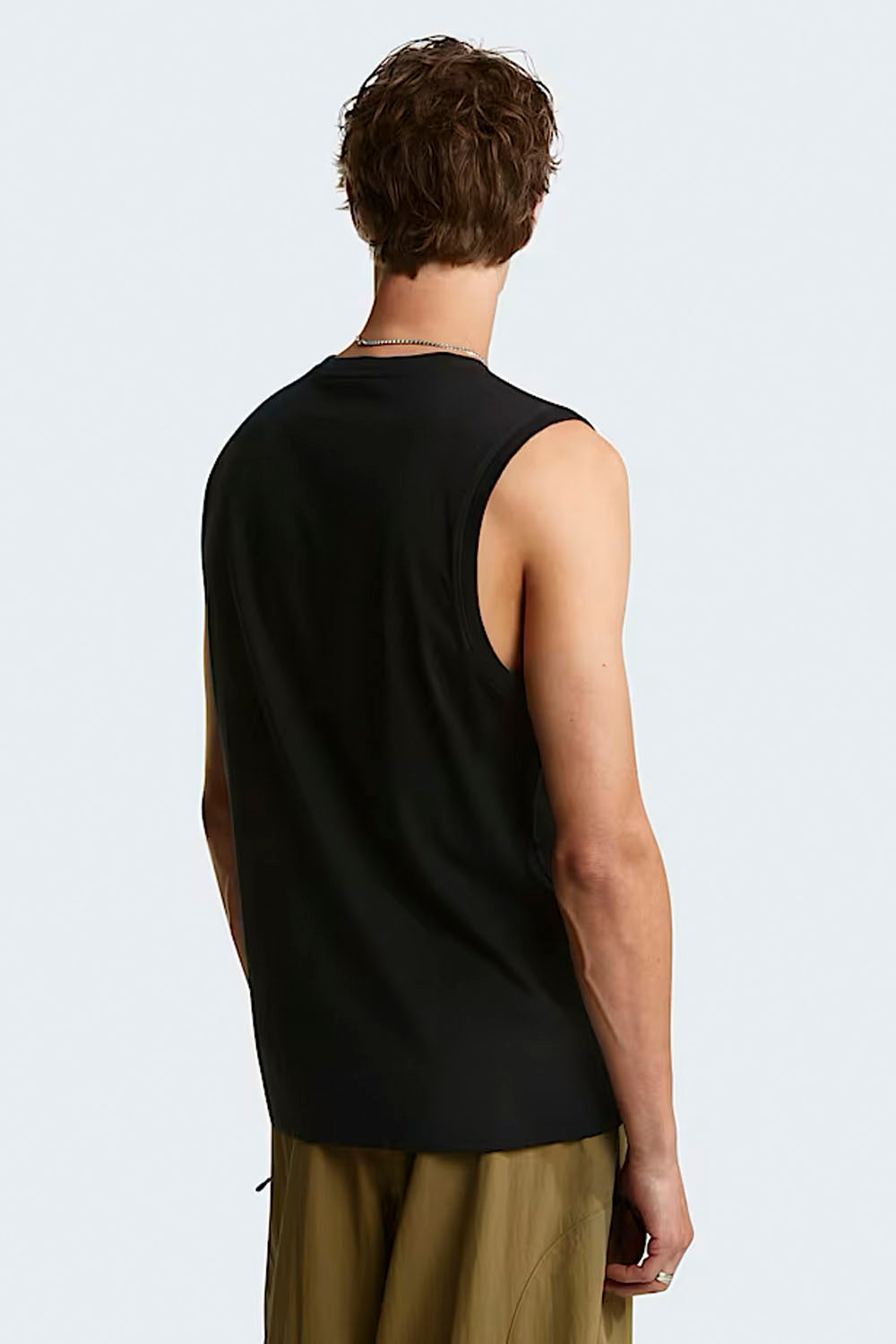 Person wearing a black sleeveless shirt on a light gray background