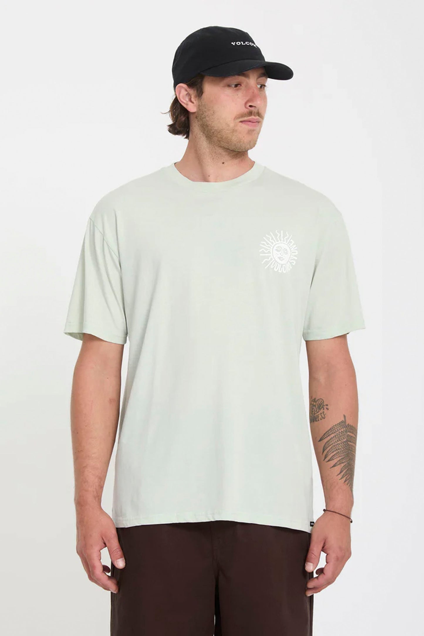 Man wearing a light green Volcom Mazatlan t-shirt and black cap on a white background