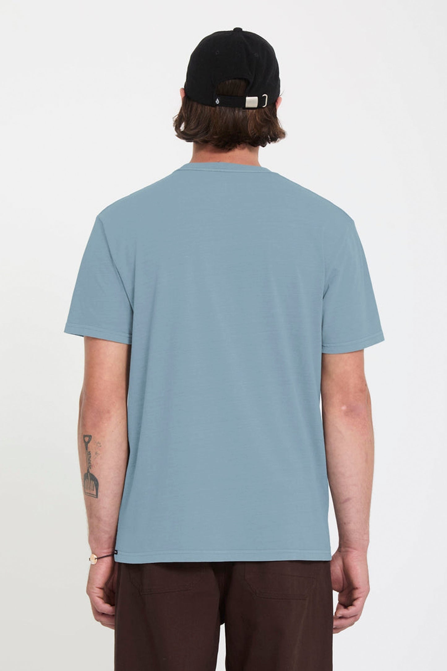 Person wearing a light blue Volcom Solid Stone t-shirt and black cap on a white background