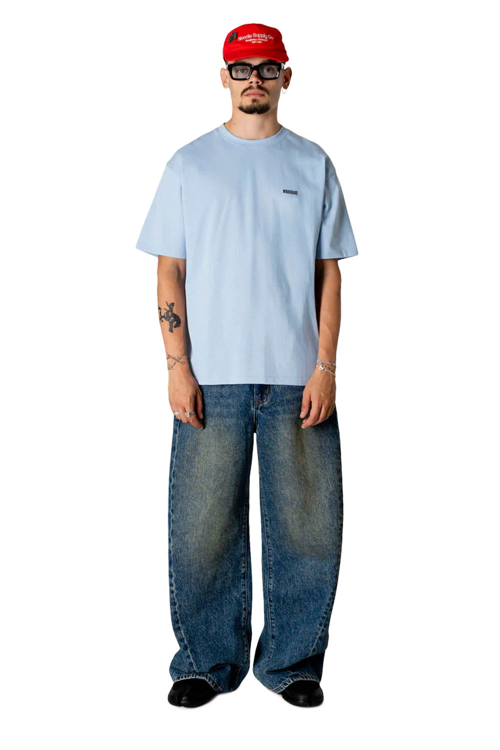Person wearing a light blue t-shirt, red cap, and jeans on a white background