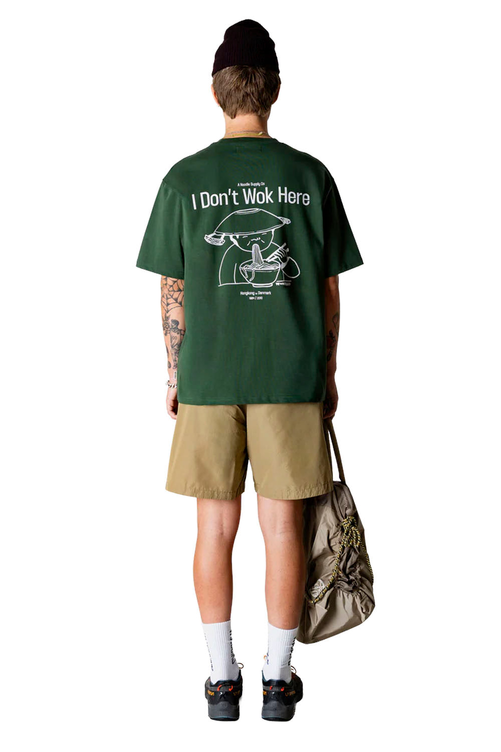 Person wearing a green t-shirt with text and graphics, standing against a white background