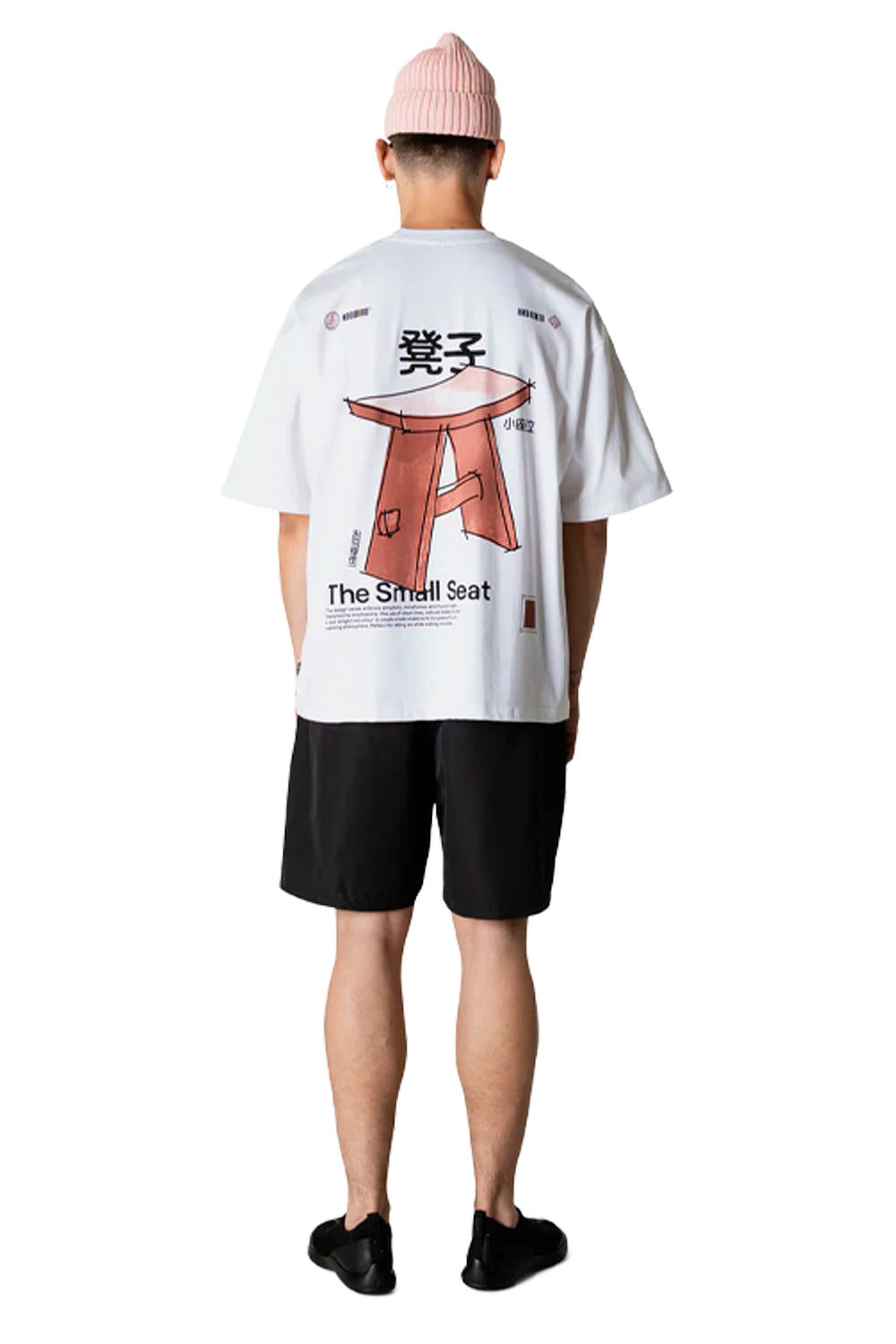 Person wearing a white t-shirt with a graphic design on the back, standing against a white background