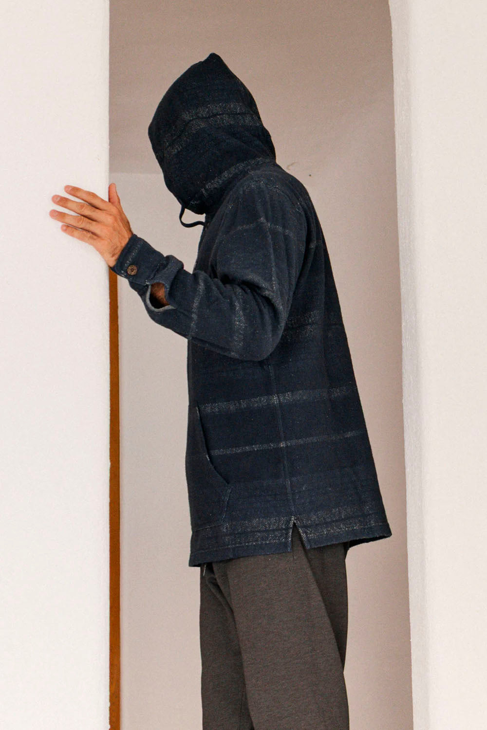 Person wearing a dark blue hooded jacket against a neutral background