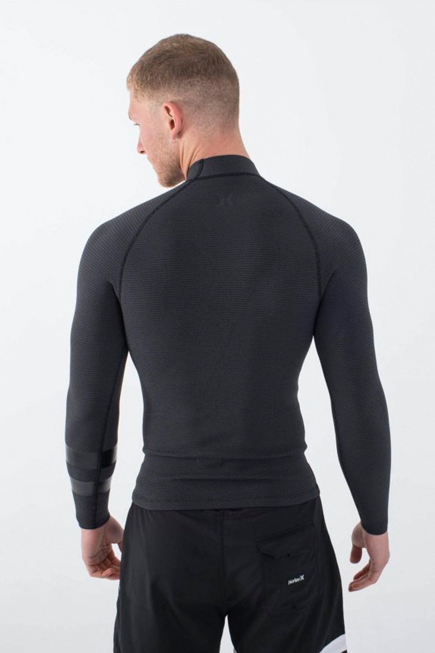 Man wearing a black long-sleeve Hurley Plus jacket on a white background