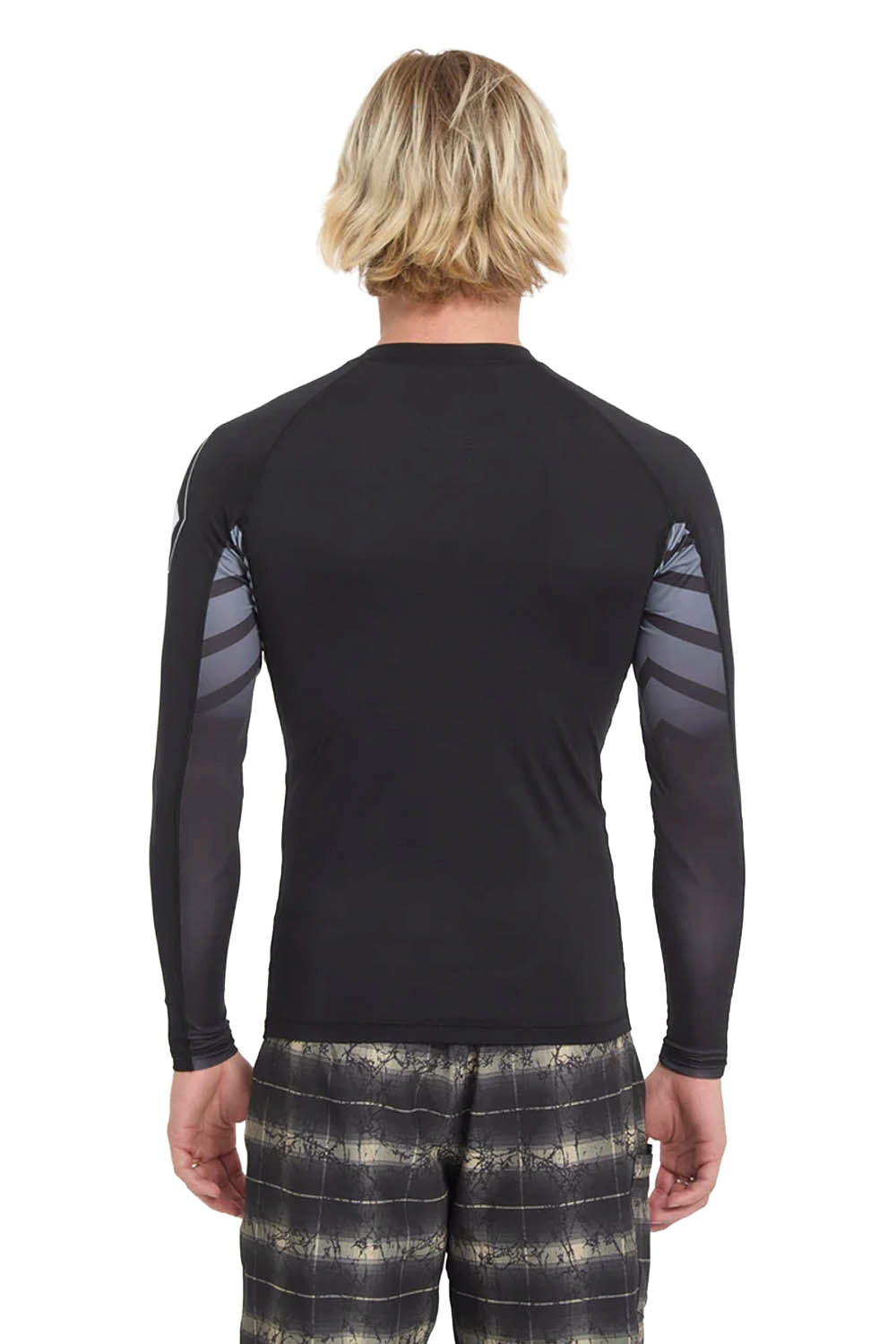 Man wearing a black Volcom long-sleeve rashguard and patterned shorts on a white background