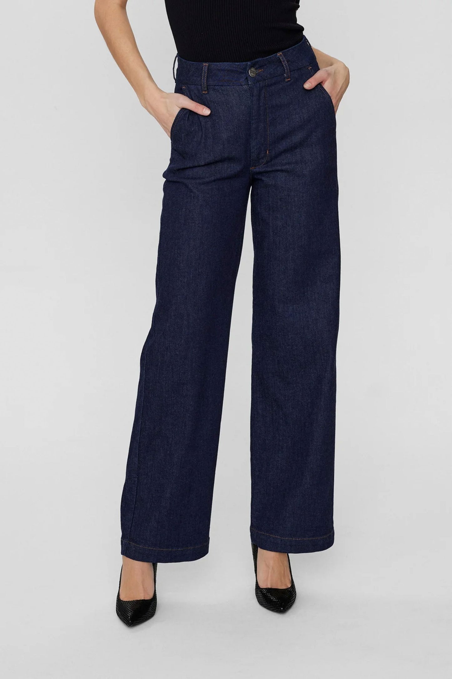 Person wearing dark blue wide-leg jeans on a white background